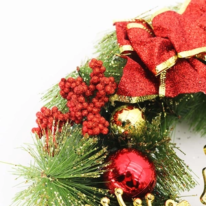 Close-up of a Christmas wreath featuring red glitter bows, gold baubles, and pine needles