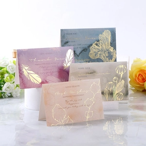Detail of elegant greeting cards with gold foil patterns on a marble surface