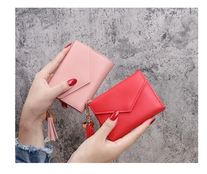 Detail of pink and red women wallets with pebble leather texture and tassel pendants