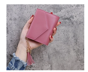 Detail of rose pink litchi grain wallet with leather tassel held in hand for size