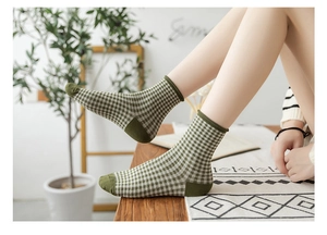 Detail of green and white gingham cotton mid-calf socks worn in a cozy home setting