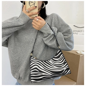 Close-up of zebra print shoulder bag featuring black and white patterns and gold zipper