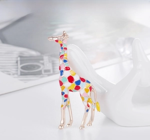 Detail of giraffe brooch with colorful enamel tiles leaning on a ceramic swan decor