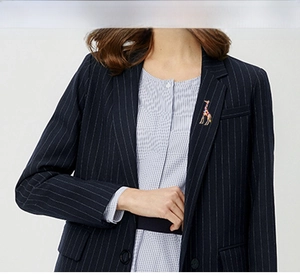 Detail of colorful giraffe enamel brooch pinned on a dark striped blazer lapel