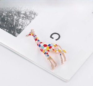 Detail of colorful enamel giraffe brooch with gold metal frame on fashion magazine