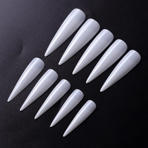 Set of 10 long white stiletto false nail tips displayed on a black textured surface