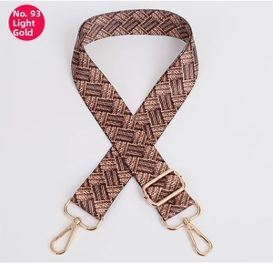 Detail of adjustable woven shoulder strap with brown and beige grid patterns and gold hooks