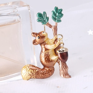 Detail showing a cute enamel squirrel brooch with acorns on a textured white surface