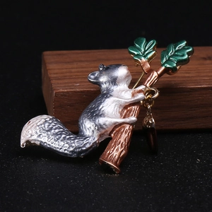 Detail of squirrel brooch with enamel finish and hanging acorn charm on wooden backdrop