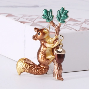 Detailed close-up of squirrel and acorn brooch with enamel finish on a geometric box