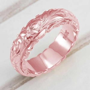 Macro shot of rose gold ring featuring detailed flower and leaf engraving and polished interior