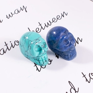 Macro shot of turquoise and deep blue gemstone skull carvings on handwritten paper