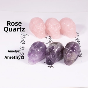 Macro shot of hand-carved rose quartz and amethyst skull crystals on decorative paper