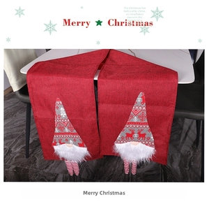 Detail of Christmas table runner with red linen fabric and long-legged gnome decorations