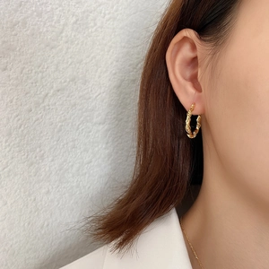 Macro view of gold twisted weave earrings on model featuring 925 sterling silver texture