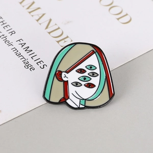 Macro detail of Picasso-style multi-eye enamel brooch pin with artistic metal outlines