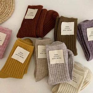 Thick wool knit socks in various earth tones with minimalist fabric tags for winter comfort