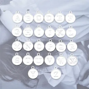 Macro detail of 26 alphabet round pendant charms in silver alloy for DIY jewelry