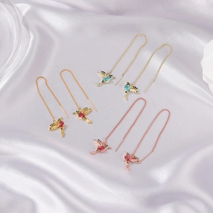 Close-up of hummingbird chain earrings in gold, rose gold and silver with colorful stones