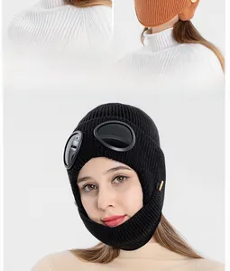 Detail of knitted aviator hat featuring decorative goggles and warm ear flaps