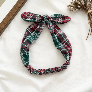 Detail of red and green plaid Christmas headband with white snowflake print and bow
