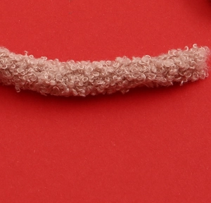 Close-up of soft beige teddy velvet reindeer horn detail on a red background