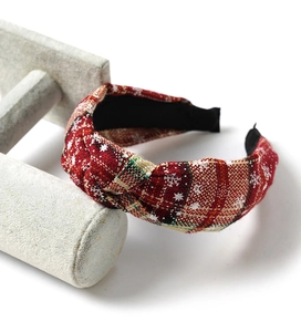 Detail of red plaid Christmas headband with white snowflake patterns and knotted design