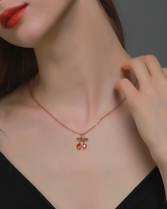 Close-up of cherry pendant necklace with red crystals and rose gold chain on model