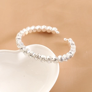 Macro shot of silver rhinestone stretch bracelet on a white heart ceramic dish