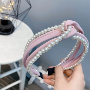 Detail of pink chiffon knotted headband with intertwined white pearls and fabric texture