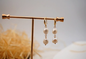 Detailed view of vintage gold drop earrings with baroque freshwater pearls on T-stand