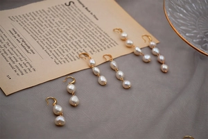 Detailed view of three freshwater pearl drop earrings in different lengths on vintage paper