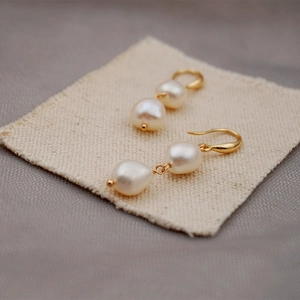 Vintage baroque freshwater pearl drop earrings with gold hooks on beige linen fabric