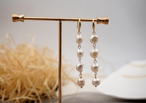 Macro detail of long Baroque freshwater pearl earrings with gold chain in vintage style