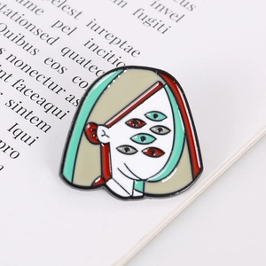 Macro shot of surreal Picasso-style five-eyed face enamel brooch on a vintage book