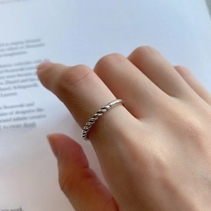 Close-up of a 925 sterling silver twisted rope ring worn on finger over minimalist background