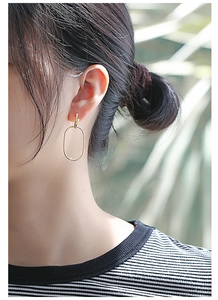 Detail of minimalist gold double hoop oval earrings shown on a female model