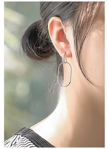Detailed view of large oval geometric silver earrings on model in natural light