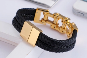Macro view of men's double-layer braided leather bracelet with golden bike chain link