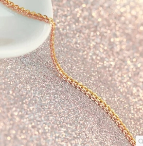 Macro view of 18K rose gold and gold plated stainless steel cross chain detail