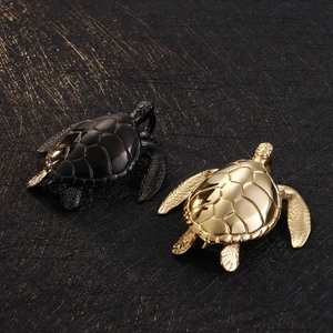 Close-up of turtle pendants in black and gold finishes on a textured dark background