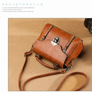 Macro detail of a vintage brown polished leather crossbody bag with silver metal clasp