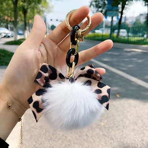Close-up of leopard print bow and white faux fur pompom keychain with golden chain