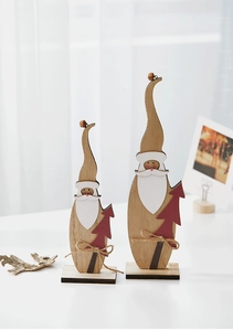 Dettaglio di Babbo Natale in legno con fiocchi di spago e campanellini sul tavolo
