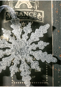 Makroaufnahme von glitzerndem Acryl-Schneeflocken-Anhänger mit Silberband auf Holz
