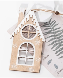 Macro shot of wooden Christmas house pendant with white roof and snowflake patterns