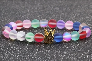Close-up of matte moonstone beads and gold crown charm with colorful rhinestones