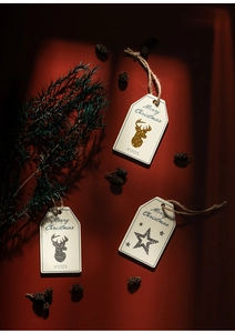 Close-up of wooden Christmas gift tags with reindeer and star patterns on red background