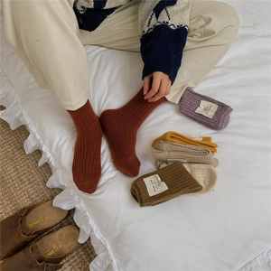 Detailed view of thick ribbed wool socks in multiple colors on a cozy bed background