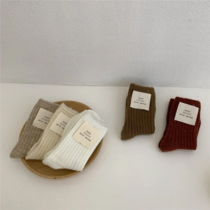 Detailed close-up of five pairs of thick ribbed wool socks in neutral earthy tones